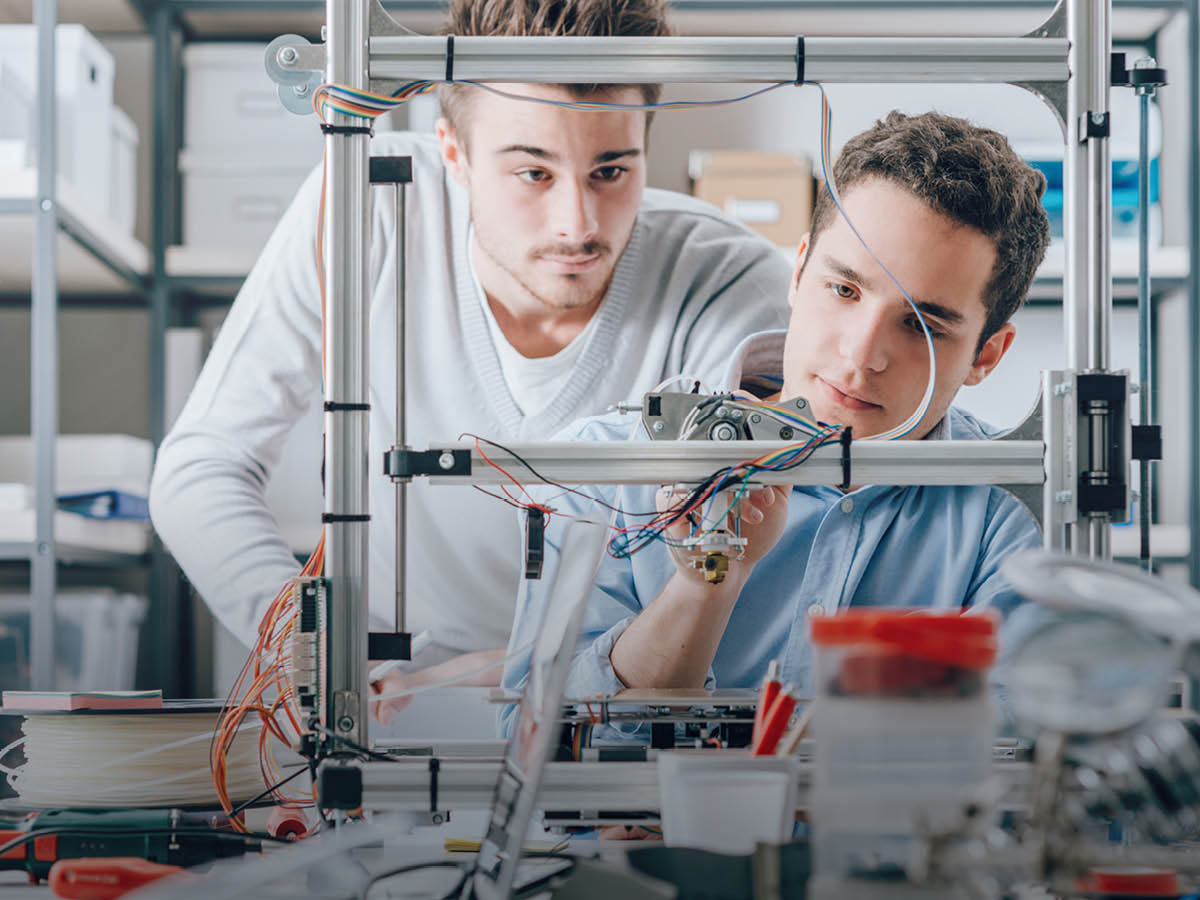 Zwei Fachkräfte arbeiten gemeinsam an einer technischen Anlage in einer modernen Werkstatt oder einem Labor.