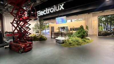 Großzügiger Electrolux-Ausstellungsbereich mit moderner Küchenpräsentation, Pflanzen und naturnaher Gestaltung; links steht eine rote Hebebühne.