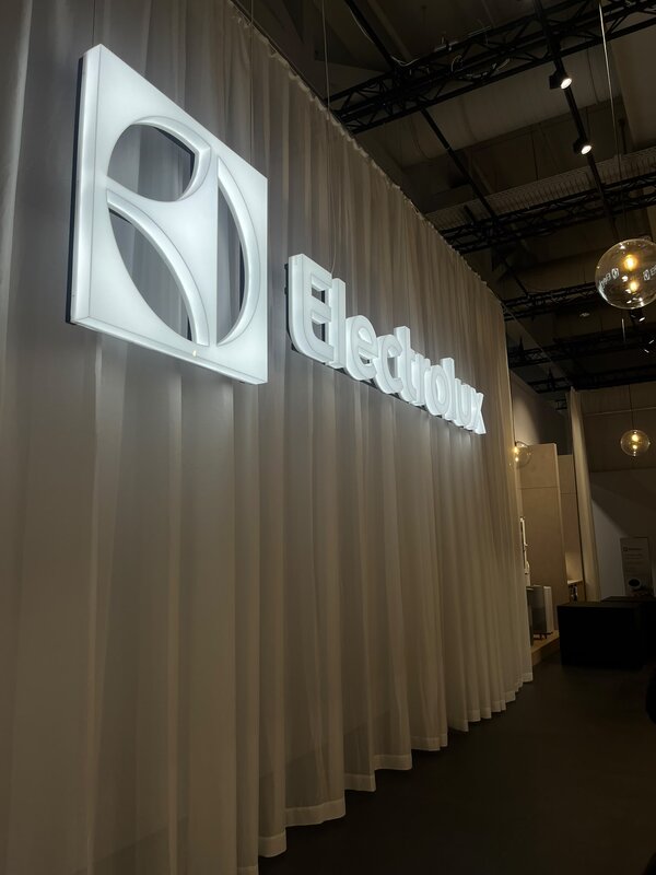 Beleuchtetes Electrolux-Logo an einer weißen Vorhangwand in einem modern gestalteten Ausstellungsraum.