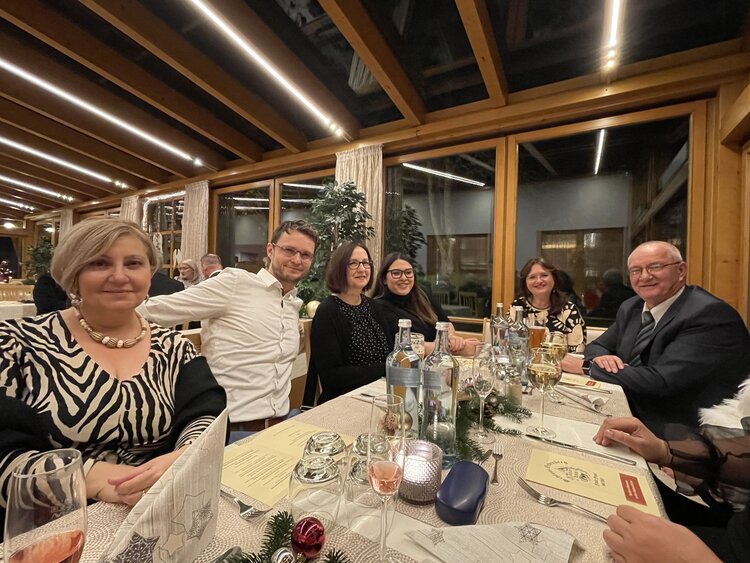 Sechs Personen sitzen im Wintergarten eines Restaurants an einem gedeckten Tisch und gucken freundlich in die Kamera.