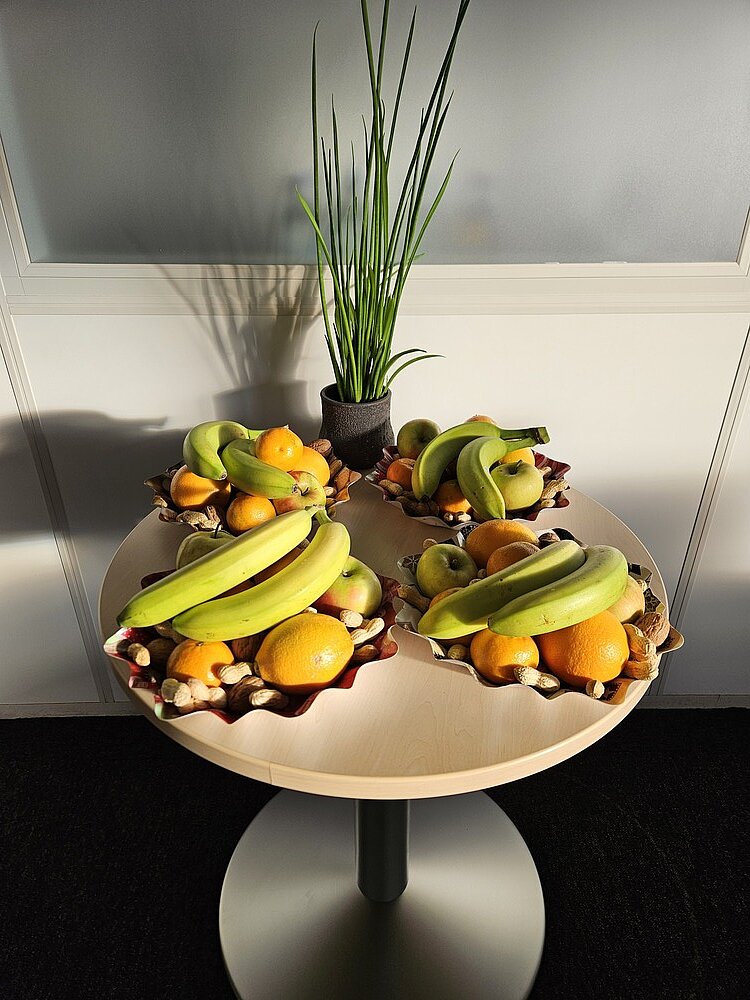 Ein Nikolausteller Auf einem Tisch liegen neben einer Vase vier Nikolausteller, die reichlich gefüllt sind mit Bananen, Mandarinen, Äpfeln, Erd- und Walnüssen.