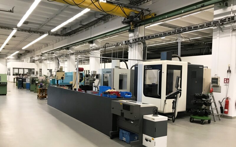 Moderner Maschinenbereich mit einer großen CNC-Bearbeitungsmaschine, weiteren Werkzeugmaschinen und einem Hallenkran.
