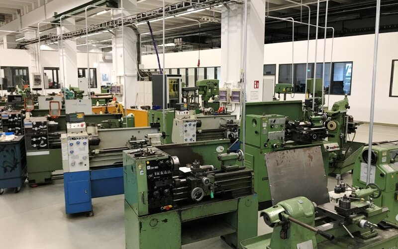 Blick in eine technische Ausbildungswerkstatt mit mehreren Drehmaschinen und weiteren Maschinen für die Metallbearbeitung.